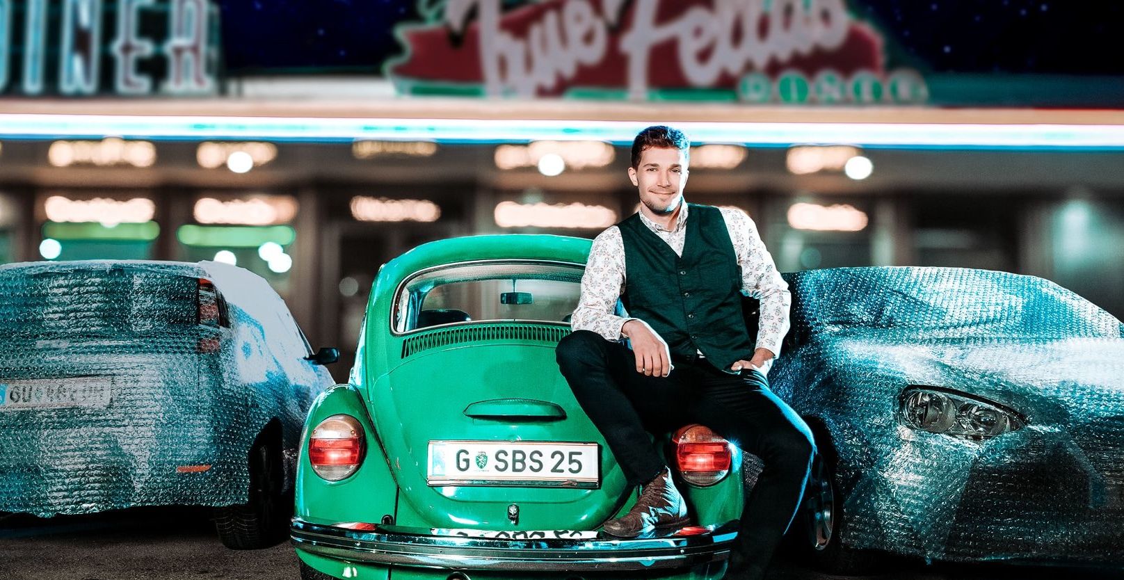 Mann lehnt an einem VW-Käfer Mann lehnt an einem VW-Käfer